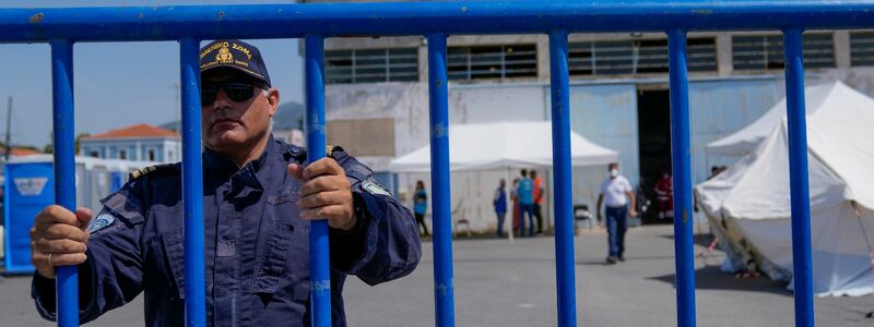Ein Offizier der Küstenwache am Eingang des Flüchtlingslagers nahe Athen. - Foto: Thanassis Stavrakis/AP/dpa