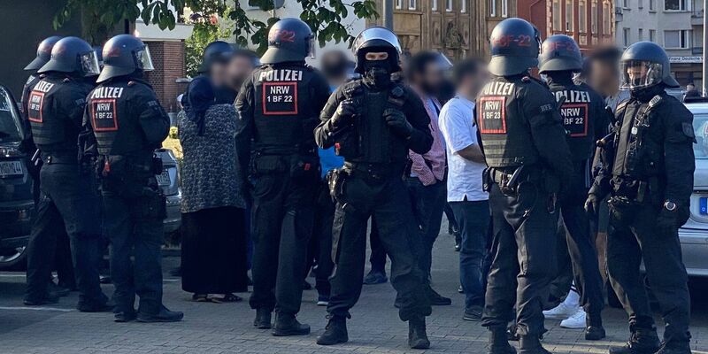 Polizisten schirmen nach der Massenschlägerei am Donnerstag eine Personengruppe ab. In der darauffolgenden Nacht versammelte sich erneut eine größere Gruppe von Menschen in der Innenstadt von Castrop-Rauxel. - Foto: Marc Gruber/7aktuell/dpa