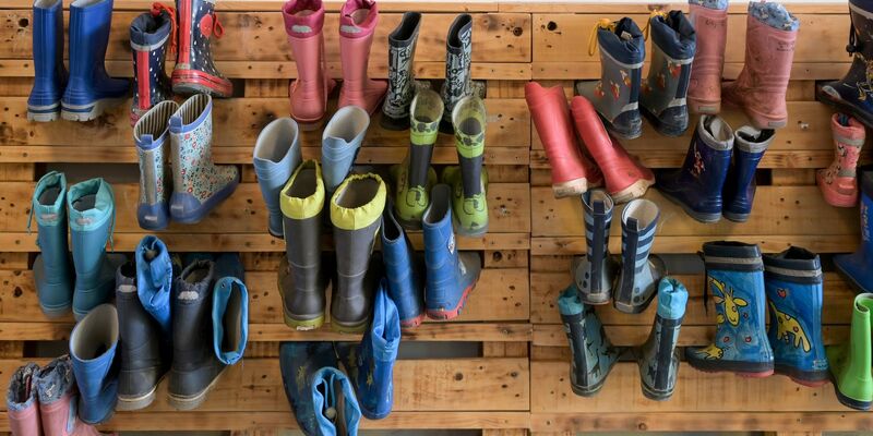Gummistiefel hängen an der Palettenwand einer Kindertagesstätte in Halle (Saale). In Deutschland fehlen Erzieherinnen und Erzieher. - Foto: Heiko Rebsch/dpa