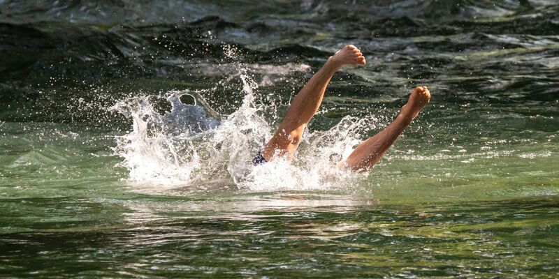 Ein junger Mann erfrischt sich mit einem Sprung in den Eisbach im Englischen Garten in München. - Foto: Peter Kneffel/dpa