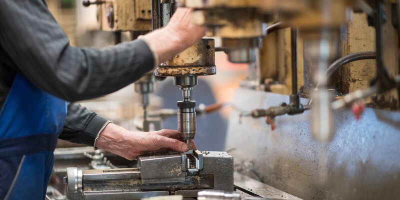 Ein Mitarbeiter bedient in einer brandenburgischen Produktionshalle eine Maschine zur Verarbeitung von Metall. Die deutsche Wirtschaft ist nach dem frostigen Konjunkturwinter auch im Frühjahr nicht in Schwung gekommen. - Foto: Monika Skolimowska/zb/dpa