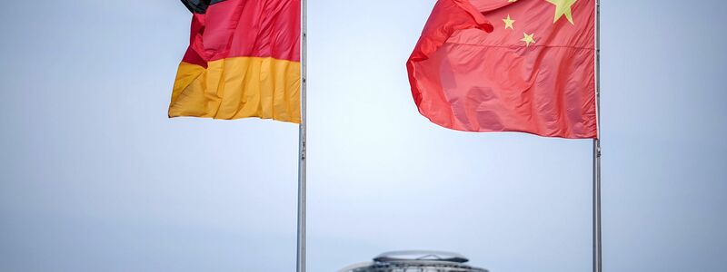 Die Flaggen von Deutschland und China wehen vor dem Bundeskanzleramt. Im Hintergrund die Kuppel des Reichstagsgebäudes. - Foto: Kay Nietfeld/dpa