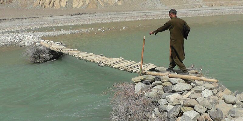 Ein Mann geht über eine hölzerne Brücke im Norden Pakistans nahe der afghanischen Grenze. Sturzfluten im hatten im vergangenen Jahr eine Brücke weggespült. - Foto: Hammad Farooqi/dpa