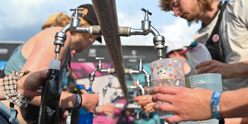 Besucher füllen beim Hurricane Festival ihre Becher und Trinkflaschen mit Wasser auf. In Deutschland steigen die Temperaturen - und die Ozon-Werte. - Foto: Lars Penning/dpa