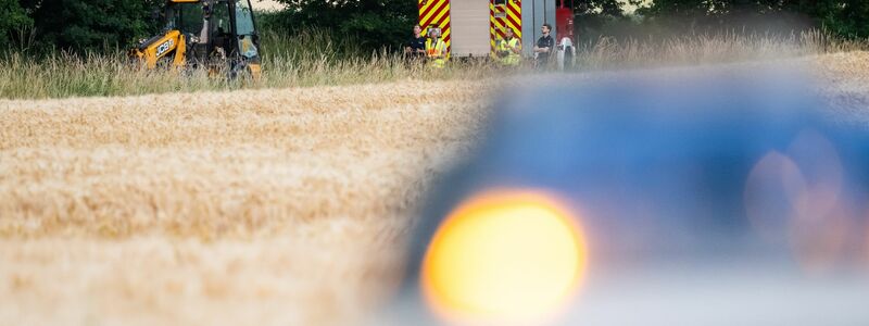 Polizisten arbeiten an der Unfallstelle, die sich hinter dem Feuerwehrfahrzeug befindet. - Foto: Philipp Schulze/dpa
