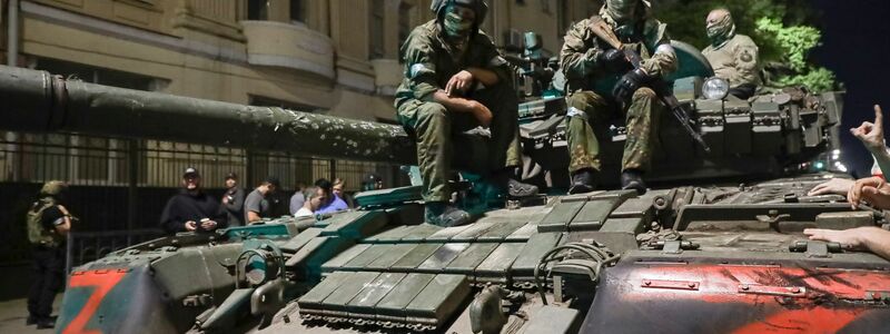 Angehörige des Militärunternehmens Wagner Group sitzen auf einem Panzer auf einer Straße in Rostow am Don, Russland, bevor sie einen Bereich im Hauptquartier des südlichen Militärbezirks verlassen. - Foto: -/AP/dpa
