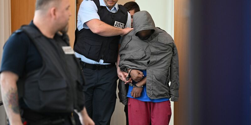 Der Angeklagte wird in Hand- und Fußschellen in den Gerichtssaal geführt. - Foto: Felix Kästle/dpa