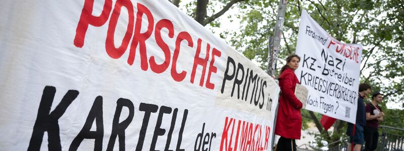 Demonstranten mit Plakaten vor Beginn der Porsche-Hauptversammlung in Stuttgart. - Foto: Marijan Murat/dpa