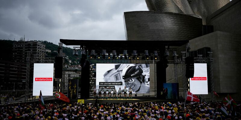 Zuschauer und Radprofis des Teams Bahrain-Victorious legen eine Schweigeminute zu Ehren des Schweizers Gino Mader ein. - Foto: Daniel Cole/AP