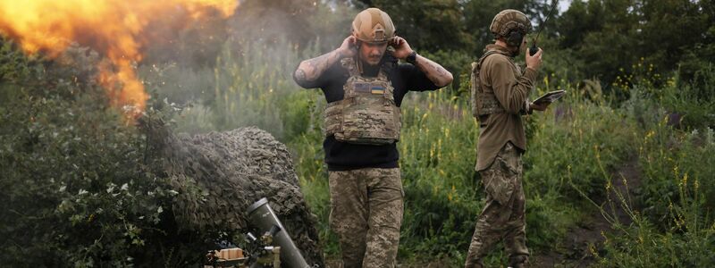 Ein ukrainischer Soldat während eines Funkgesprächs, während ein anderer Soldat 82-mm-Mörser auf russische Stellungen an der Frontlinie in der Nähe Bachmut feuert. - Foto: Alex Babenko/AP/dpa