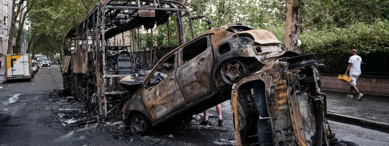 Ausgebrannte Autos und ein Bus stehen in einer Straße in Lyon. - Foto: Laurent Cipriani/AP