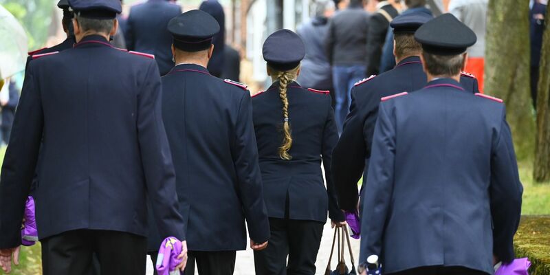 Feuerwehrleute in Uniform vor Beginn des Gottesdienstes in Toppenstedt. - Foto: Jonas Walzberg/dpa