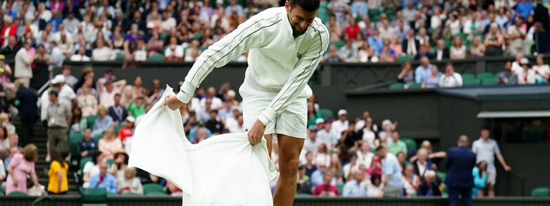 Novak Djokovic trocknet während der Regenunterbrechung den Rasen. - Foto: Zac Goodwin/PA Wire/dpa
