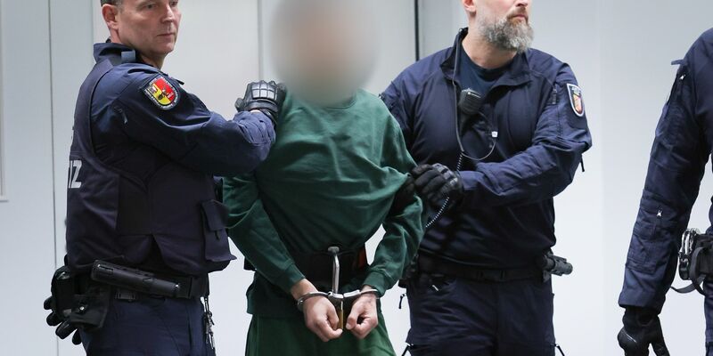 Der Angeklagte Ibrahim A. wird von Justizbeamten an seinen Platz im Gerichtssaal gebracht. - Foto: Christian Charisius/dpa