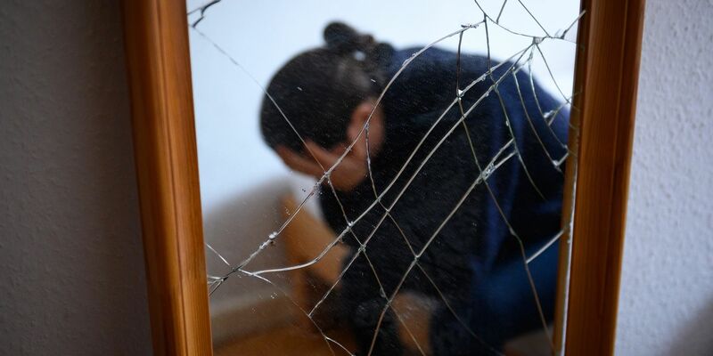 Eine Frau sitzt neben einem gesprungenen Spiegel auf einem Bett und hält ihren Kopf in den Händen. (Symbolbild) - Foto: Jonas Walzberg/dpa