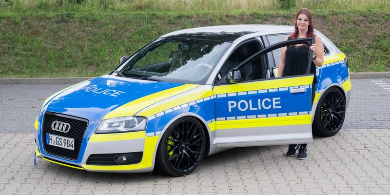 Die Autotunerin Svenja Geertz steht neben ihrem Audi, der ähnlich wie ein Polizeifahrzeug foliert ist. - Foto: Julian Stratenschulte/dpa