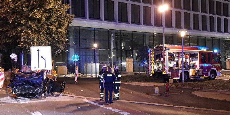 Einsatzkräfte der Feuerwehr und Polizei stehen neben einem zerstörtem Wagen an der Unfallstelle in München. - Foto: -/Berufsfeuerwehr München/dpa