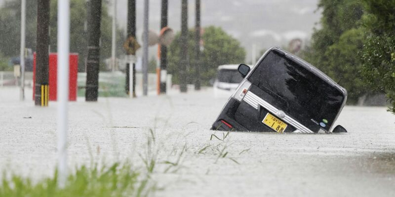 Ein Fahrzeug steckt auf einer überfluteten Straße in der Präfektur Fukuoka fest. - Foto: Uncredited/Kyodo News/AP