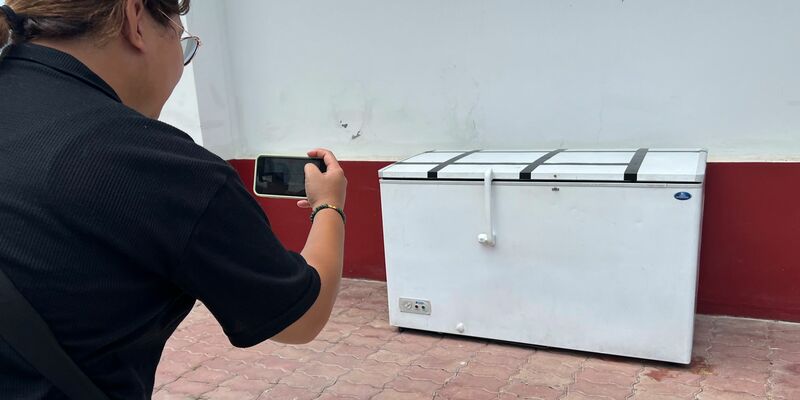 Eine Reporterin fotografiert die Kühltruhe, in der die Leiche des 62-jährigen Deutschen gefunden worden war. Nun hat die Polizei einen Verdächtigen festgenommen. - Foto: Uncredited/AP