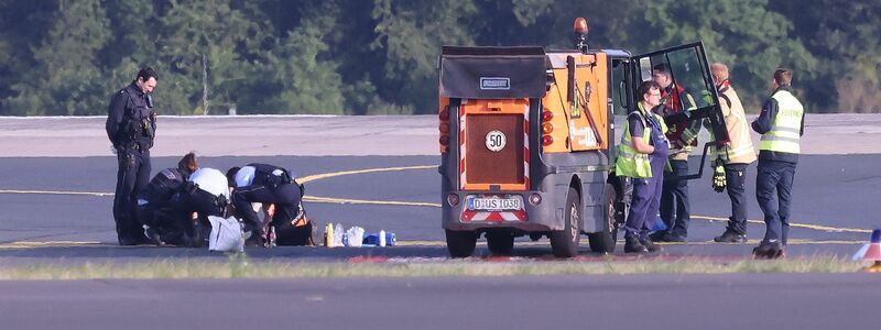 Sicherheitspersonal und Polizisten versuchen am Düsseldofer Flughafen, Aktivisten vom Asphalt auf dem Rollfeld zu lösen. - Foto: David Young/dpa