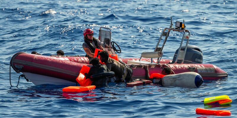 Ein Mitglied der spanischen Nichtregierungsorganisation Open Arms hilft Migranten, an Bord zu kommen. Viele Minderjährige sterben während der Flucht. - Foto: Francisco Seco/AP/dpa