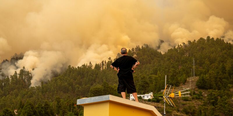 Durch einen Waldbrand erzeugter Rauch steigt hinter einem Wohnhaus in den Himmel. - Foto: Europa Press/EUROPA PRESS/dpa
