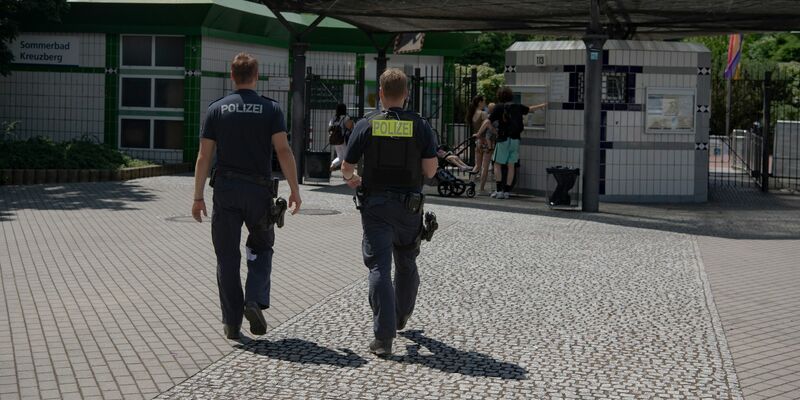 Zwei Polizsten der Mobilen Wache gehen auf das Prinzenbad in Kreuzberg zu. - Foto: Paul Zinken/dpa