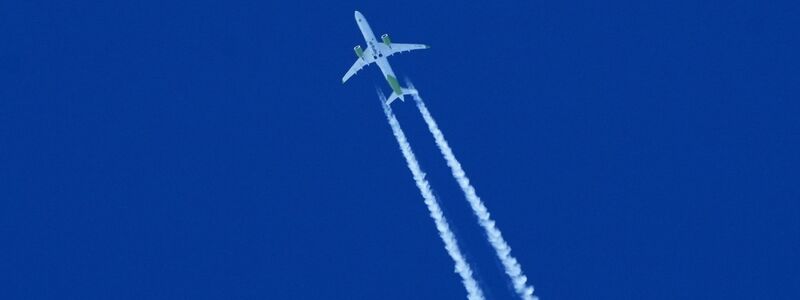 Ein Flugzeug zieht am Himmel einen Kondensstreifen hinter sich her. - Foto: Soeren Stache/dpa
