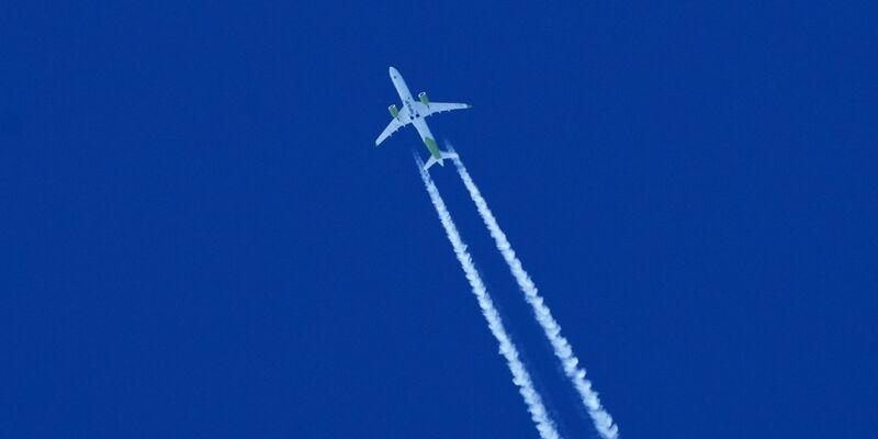 Ein Flugzeug zieht am Himmel einen Kondensstreifen hinter sich her. - Foto: Soeren Stache/dpa