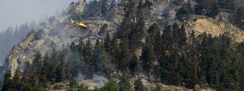 Ein Helikopter ist zur Bekämpfung des Waldbrandes nahe Bitsch im Einsatz. - Foto: Jean-Christophe Bott/KEYSTONE/dpa