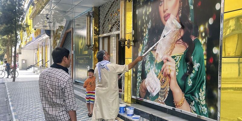 Ein Mitarbeiter eines Schönheitssalons übermalt nach der Machtübernahme der Taliban das Bild einer Frau in Kabul (Archivbild). Frauen haben in der afghanischen Hauptstadt gegen die Schließung der Salons protestiert. - Foto: -/Kyodo/dpa