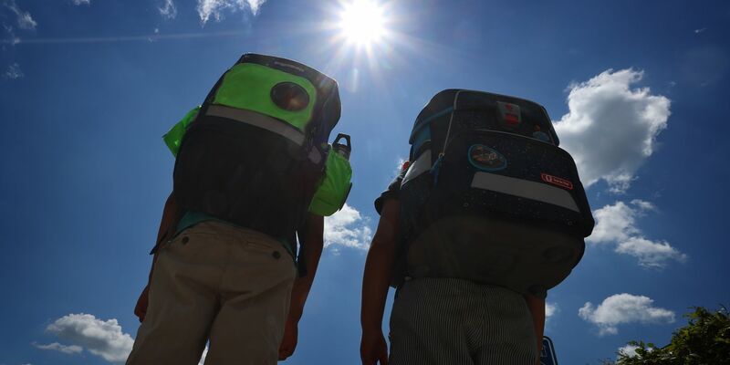 Zwei Kinder laufen mit ihren Schulranzen im Sonnenschein. - Foto: Karl-Josef Hildenbrand/dpa