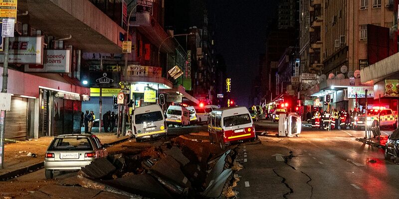 Die mutmaßliche Gasexplosion hat ein Loch in die Straße gerissen. - Foto: Shiraaz Mohamed/AP/dpa