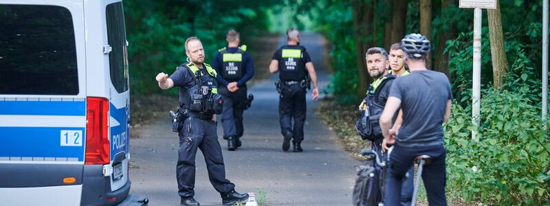 Polizisten stehen am Eingang eines Waldgebietes in dem sich die Raubkatze befinden soll. - Foto: Annette Riedl/dpa