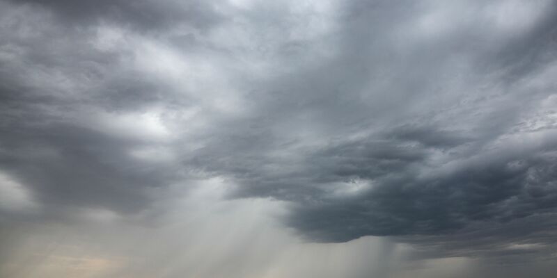 Eine Regenfront zieht über ein Getreidefeld hinweg. - Foto: Jan Woitas/dpa