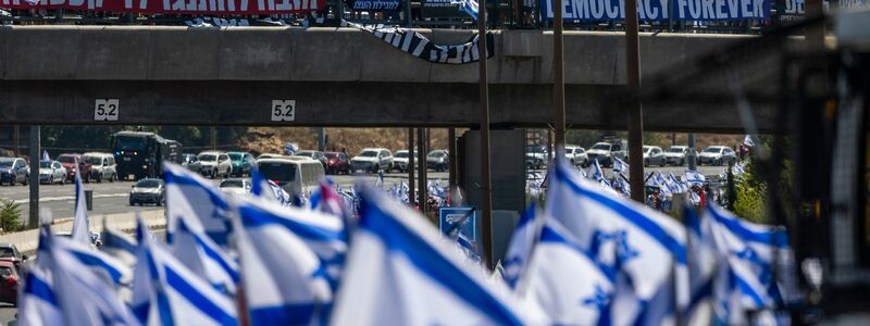 Tausende israelische Demonstranten marschieren entlang einer Autobahn, um gegen die geplante Justizreform der Regierung zu protestieren. - Foto: Ilia Yefimovich/dpa