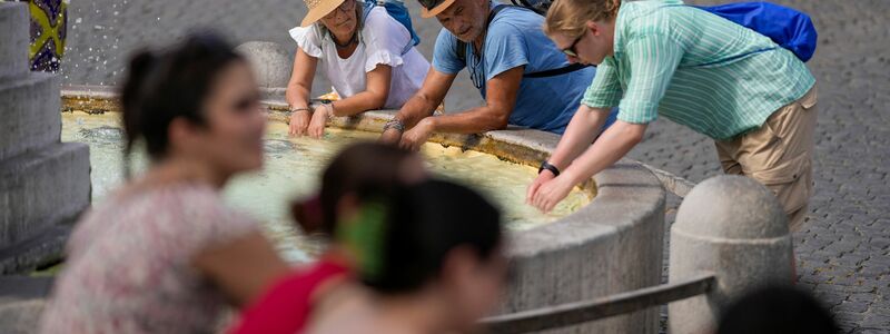 Touristen erfrischen sich bei ihrem Besuch in Rom an einem Brunnen. - Foto: Andrew Medichini/AP
