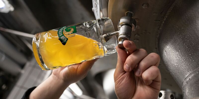 Ein Braumeister entnimmt Bier aus einem Tank. Weltweit wurde 2022 mehr Bier produziert als erwartet. - Foto: Marijan Murat/dpa