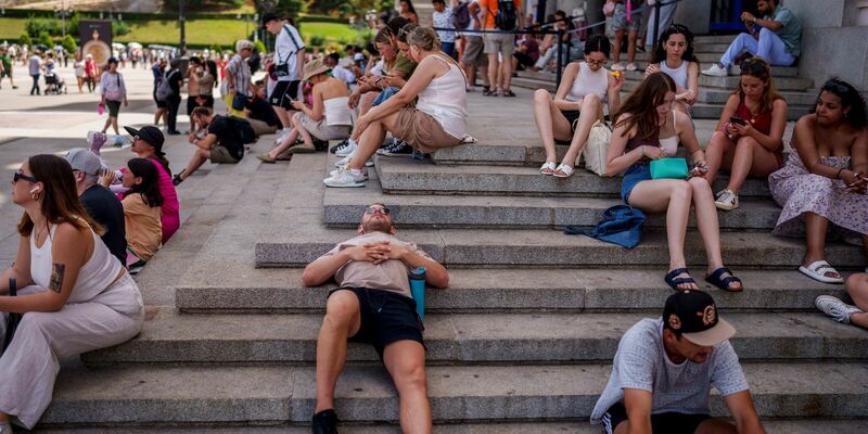 Menschen ruhen sich an einem heißen und sonnigen Sommertag in Madrid aus. - Foto: Manu Fernandez/AP/dpa