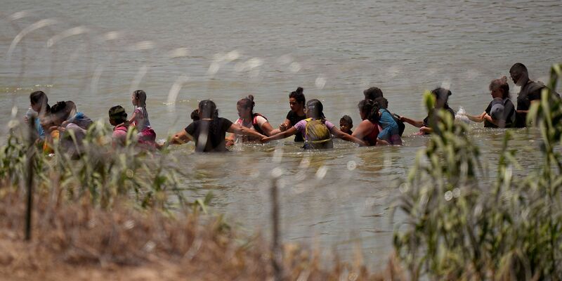 Migranten überqueren Hand in Hand den Fluss Rio Grande zwischen Mexiko und den USA. - Foto: Eric Gay/AP