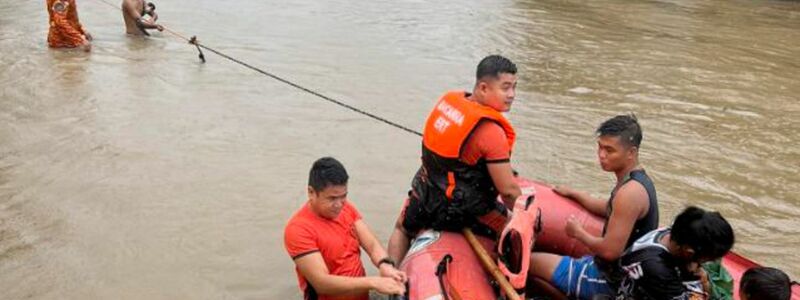 Rettungskräfte verwenden ein Gummiboot, um die Bewohner in höher gelegene Gebiete zu evakuieren. - Foto: Uncredited/Philippine Coast Guard/AP/dpa