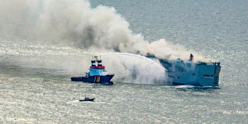 Eine Luftaufnahme zeigt einen deutschen Notschlepper(l), der das Feuer auf dem brennenden Frachter «Fremantle Highway» bekämpft. - Foto: Herman IJsseling/FLYING FOCUS aerial photography/dpa
