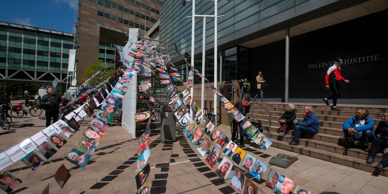 Fotos von Klägern hängen vor einem Gericht in Den Haag, in dem ein Klimaprozess gegen den Öl- und Erdgaskonzern Shell stattfindet (Archivbild). - Foto: Peter Dejong/AP/dpa