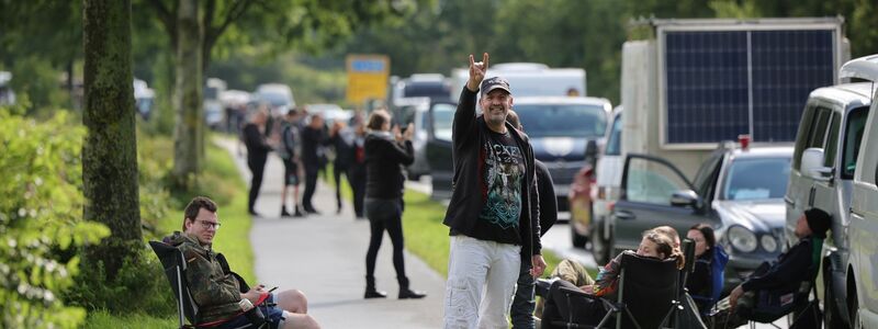 Metal-Fans gehen über das schlammige Festivalgelände. - Foto: Christian Charisius/dpa