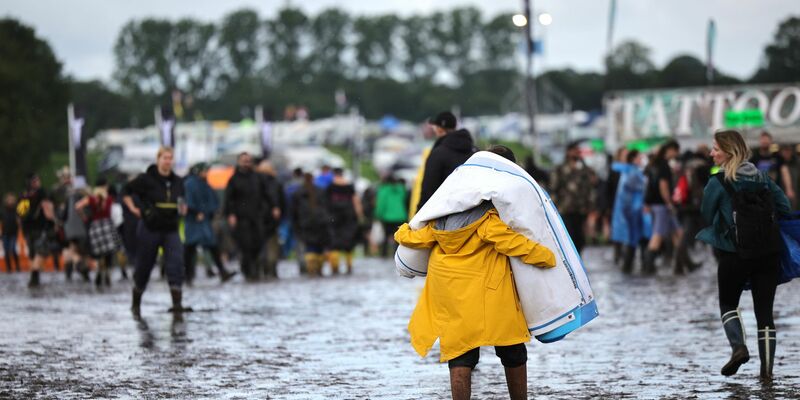 Metal-Fans sind auf dem schlammigen Festivalgelände unterwegs. - Foto: Christian Charisius/dpa
