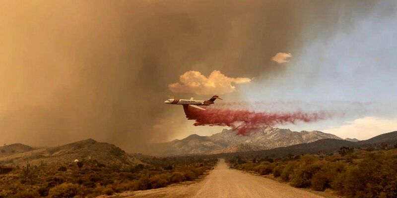 Ein Löschflugzeug ist über dem Mojave National Preserve im Einsatz, einem Schutzgebiet im US-Bundesstaat Kalifornien. - Foto: R. Almendinger/National Park Service Mojave National Preserve/AP/dpa