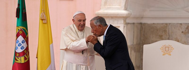 Bei der Willkommenszeremonie küsst der portugiesische Präsident Marcelo Rebelo de Sousa die Hand von Papst Franziskus. - Foto: Armando Franca/AP/dpa