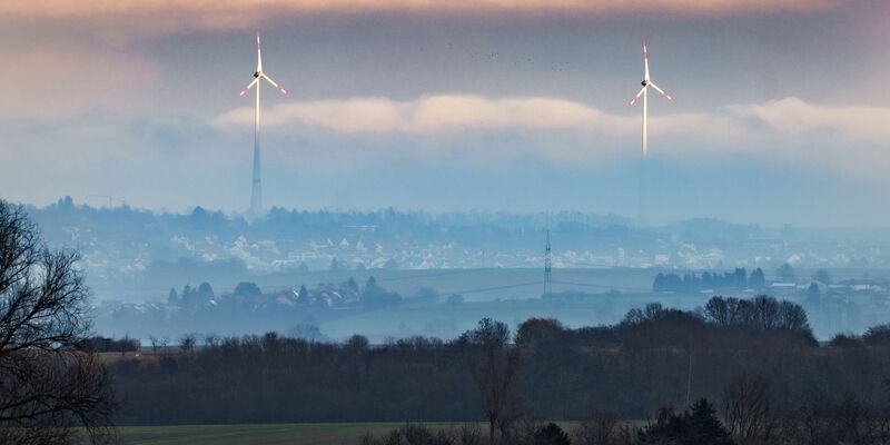Zwei Windräder ragen aus dem Dunst über der Wetterau heraus. - Foto: Frank Rumpenhorst/dpa