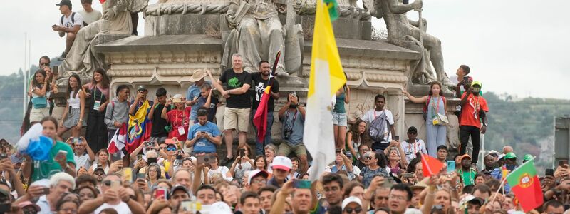 Menschen warten vor dem Präsidentenpalast auf die Ankunft des Papstes. Zehntausende Gläubige jubelten dem Pontifex zu und begrüßten ihn mit Fahnen und Postern. - Foto: Gregorio Borgia/AP/dpa