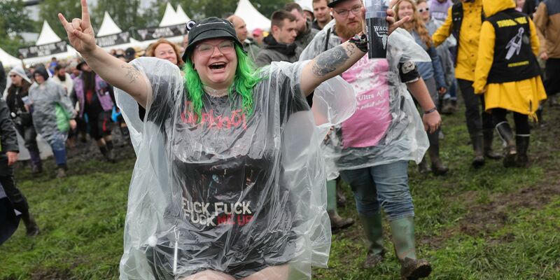 Metal-Fans laufen auf dem nassen Festivalgelände. - Foto: Christian Charisius/dpa